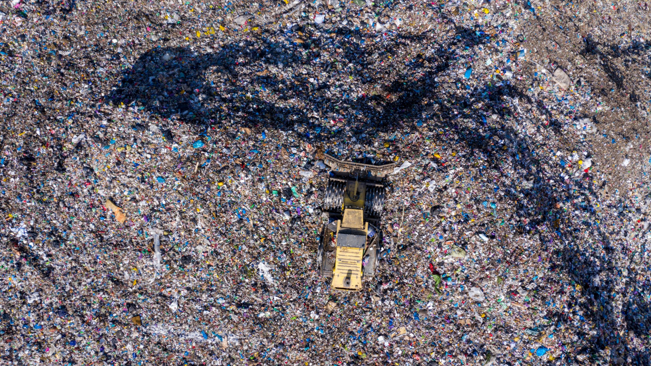 Aerial top drone view of large garbage pile, trash dump, landfill, waste from household dumping site, excavator machine is working on a mountain of garbage. Consumerism and contamination concept