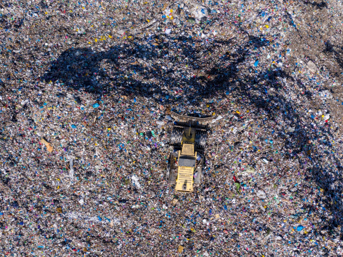 Aerial top drone view of large garbage pile, trash dump, landfill, waste from household dumping site, excavator machine is working on a mountain of garbage. Consumerism and contamination concept